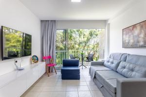 a living room with a couch and a large window at Flat Marupiara 220 - Muro Alto, Porto de Galinhas in Porto De Galinhas