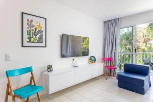 a living room with a tv and two chairs at Flat Marupiara 220 - Muro Alto, Porto de Galinhas in Porto De Galinhas +47 photos