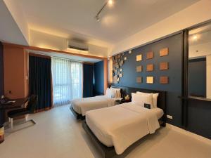 a hotel room with two beds and a desk at KL Serviced Residences Managed by HII in Manila