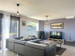 a living room with a couch and a tv at Maison Lévi avec vue mer et à 200m du port in Digosville