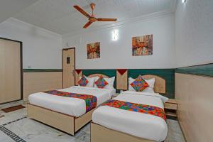 a bedroom with two beds and a ceiling fan at FabHotel The Black Diamond in Bengaluru