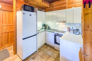 a kitchen with white appliances and wooden cabinets at Lomahuoneisto Revontuli 1 in Ukkohalla