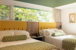 een hotelkamer met twee bedden en een raam bij Sloh Hotel & Bar Manila Medellin in Medellín +26 foto's