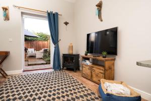 a living room with a large flat screen tv at Dog friendly cottage with hot tub under 350 steps to dunes in Winterton-on-Sea