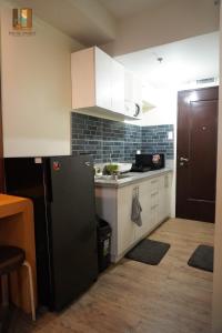 a kitchen with a black refrigerator and white cabinets at Pause Point - Standford 3 Suites in Silang +10 photos