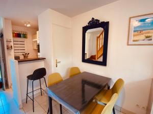 a dining room with a table and chairs and a mirror at Serena Entre mer et forêt in Camiers