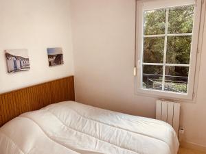 a bed in a room with a window at Serena Entre mer et forêt in Camiers