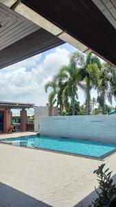 a swimming pool with palm trees in the background at The Horizon Villa Songkhla in Ban Mai