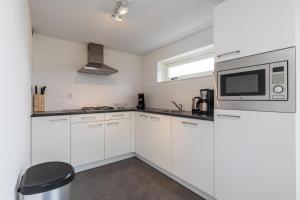 a kitchen with white cabinets and a microwave at Welcome in - Strandvilla's dichtbij het strand - Vakantiepark Zonnedorp Renesse in Renesse