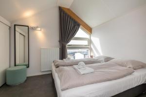 a bedroom with a large white bed with a window at Welcome in - Strandvilla's dichtbij het strand - Vakantiepark Zonnedorp Renesse in Renesse +60 photos