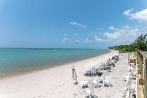 a beach with chairs and umbrellas and the ocean at Flat Marupiara 220 - Muro Alto, Porto de Galinhas in Porto De Galinhas