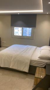 un letto con lenzuola bianche e una finestra in una stanza di Zm apartment shehab Vib a Giza