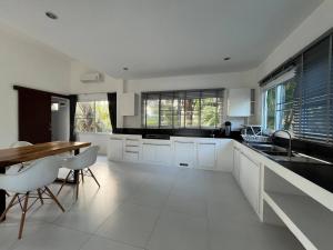eine Küche mit weißen Schränken und einem Holztisch in der Unterkunft Tranquil Oasis in Taling Ngam 2-Bedroom Pool Villa in Ban Phang Ka