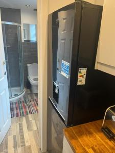 a black refrigerator in a bathroom with a toilet at George Guest House in Stoke on Trent