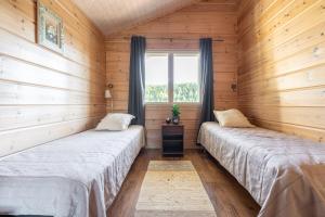 zwei Betten in einem Zimmer mit Holzwänden in der Unterkunft Karkutahko Villas 1B - Spacious 3BR Villa in Tahko with Private Sauna in Tahkovuori