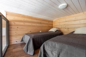 zwei Betten in einem Zimmer mit Holzwänden in der Unterkunft Karkutahko Villas 1B - Spacious 3BR Villa in Tahko with Private Sauna in Tahkovuori
