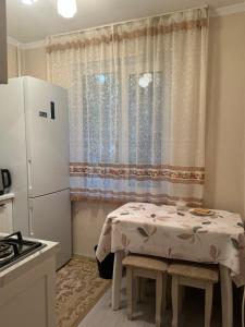a small kitchen with a table and a refrigerator at Квартира в районе Esentai Mall in Almaty