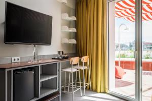 a room with a desk with a television and a sliding glass door at BYPILLOW Flamant in Barcelona