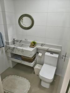 a white bathroom with a toilet and a sink at Apartamento aconchegante com ar, secadora e adega in Piratuba +21 photos