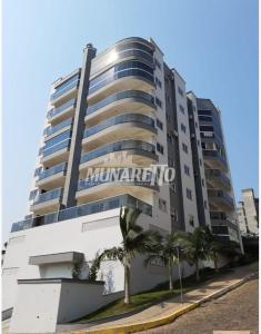 ein großes Apartmenthaus mit Palmen davor in der Unterkunft Apartamento aconchegante com ar, secadora e adega in Piratuba