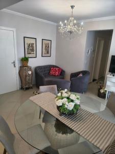ein Wohnzimmer mit einem Glastisch mit Blumen darauf in der Unterkunft Apartamento aconchegante com ar, secadora e adega in Piratuba