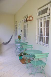 a patio with green tables and chairs and a window at Soufriere Guesthouse in Soufrière