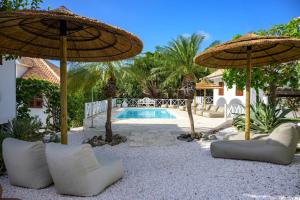 een patio met parasols en stoelen en een zwembad bij Botanique Bungalows Westpunt in Sabana Westpunt