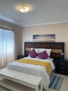 a bedroom with a large bed with purple and yellow pillows at Kelpmeeu Self- Catering and Car hire in Swakopmund