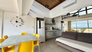 a kitchen and living room with a clock on the wall at Casa Oxente - 2da praia condominio com piscina in Cayru