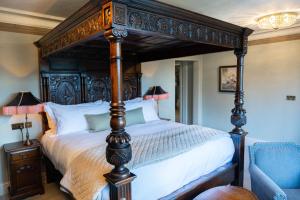 a bedroom with a large bed with a wooden canopy at Lewtrenchard Manor in Lewdown