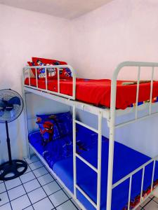 a room with two bunk beds with red and blue sheets at Griya Backpacker Pak yon in Malang