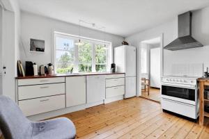 Una cocina con electrodomésticos blancos y suelo de madera. en LN2028-Hjorring-Mollebakkevej-235-B, en Vester Vidstrup