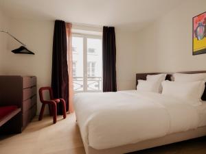 a bedroom with a white bed and a red chair at Edgar Suites - Lemercier in Paris