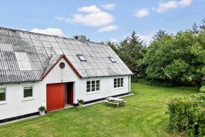 una casa blanca con una puerta roja en un patio en LN2028-Hjorring-Mollebakkevej-235-B, en Vester Vidstrup