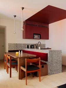 a kitchen with red cabinets and a wooden table and chairs at Edgar Suites - Lemercier in Paris