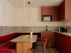 a kitchen with a table and a red couch at Edgar Suites - Lemercier in Paris