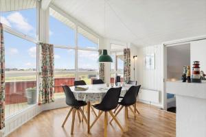 a dining room with a table and chairs and large windows at LN2020-Hjorring-Fjorden-2 in Lønstrup