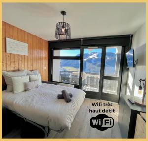 Un dormitorio con una cama grande con una ventana grande. en Le Balcon d'Avoriaz I Studio I Morzine, en Morzine