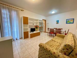 a living room with a couch and a dining room at Comfortable flat with shared pool in Porto Santa Margherita di Caorle