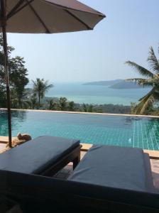 a swimming pool with an umbrella and a table at Villa Taling Ngam Amazing Sea view in Taling Ngam Beach