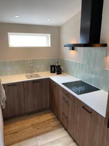 Una cocina con armarios de madera y un fregadero y una ventana. en Appartement Oisterwijk, en Moergestel