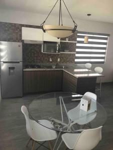 a kitchen with a glass table and white chairs at La Hidalgo, Departamento A in Chapala +4 photos