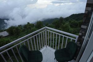 a balcony with two chairs and a view of the mountains at Elite Peak Hotel in Kasauli