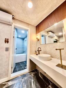 a bathroom with a sink and a mirror and a shower at Beaver Stay, Bosu in Busan