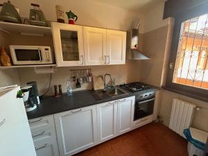 a kitchen with white cabinets and a sink and a microwave at Colonia del Lago - Trilocale - Menaggio in Menaggio
