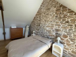 a bed in a room with a stone wall at Nature break in a farmhouse near Vannes in Grand-Champ