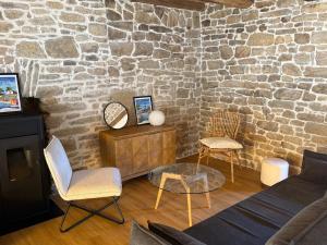 a living room with a couch and chairs and a stone wall at Nature break in a farmhouse near Vannes in Grand-Champ