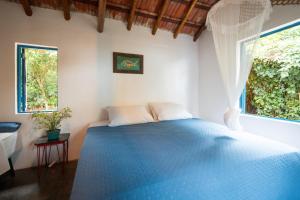 a bedroom with a blue bed and two windows at Refugio Ilha Grande in Angra dos Reis +28 photos