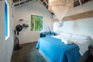 a bedroom with a bed with blue sheets and a window at Refugio Ilha Grande in Angra dos Reis