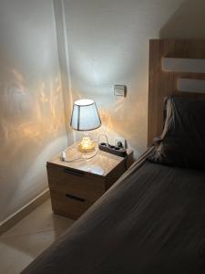 une lampe sur une table de nuit à côté d'un lit dans l'établissement réside, à Oulad Akkou